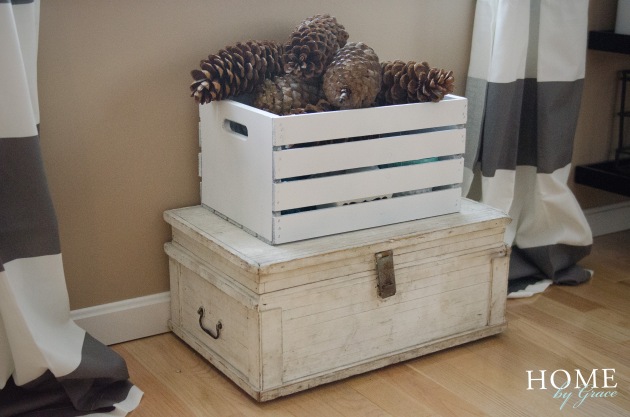 large sugar pine cones in a white wood crate on a vintage white wood chest with striped curtains